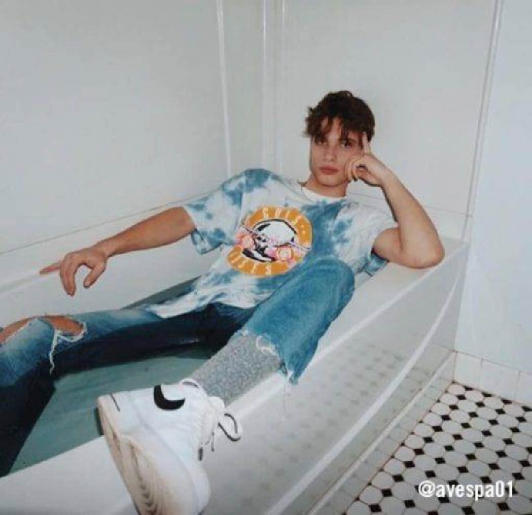 @avespa01 posing in a bath tub wearing distressed denim and a tie-dye Guns n Roses graphic tee–a 90's-inspired rock fit. 