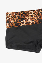 Close-up of a pair of black underwear or shorts with a leopard print waistband, shown on a plain light background.