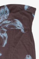 Close-up of a dark brown strapless top or dress featuring a large white and light blue lily floral print, shown against a plain light background.
