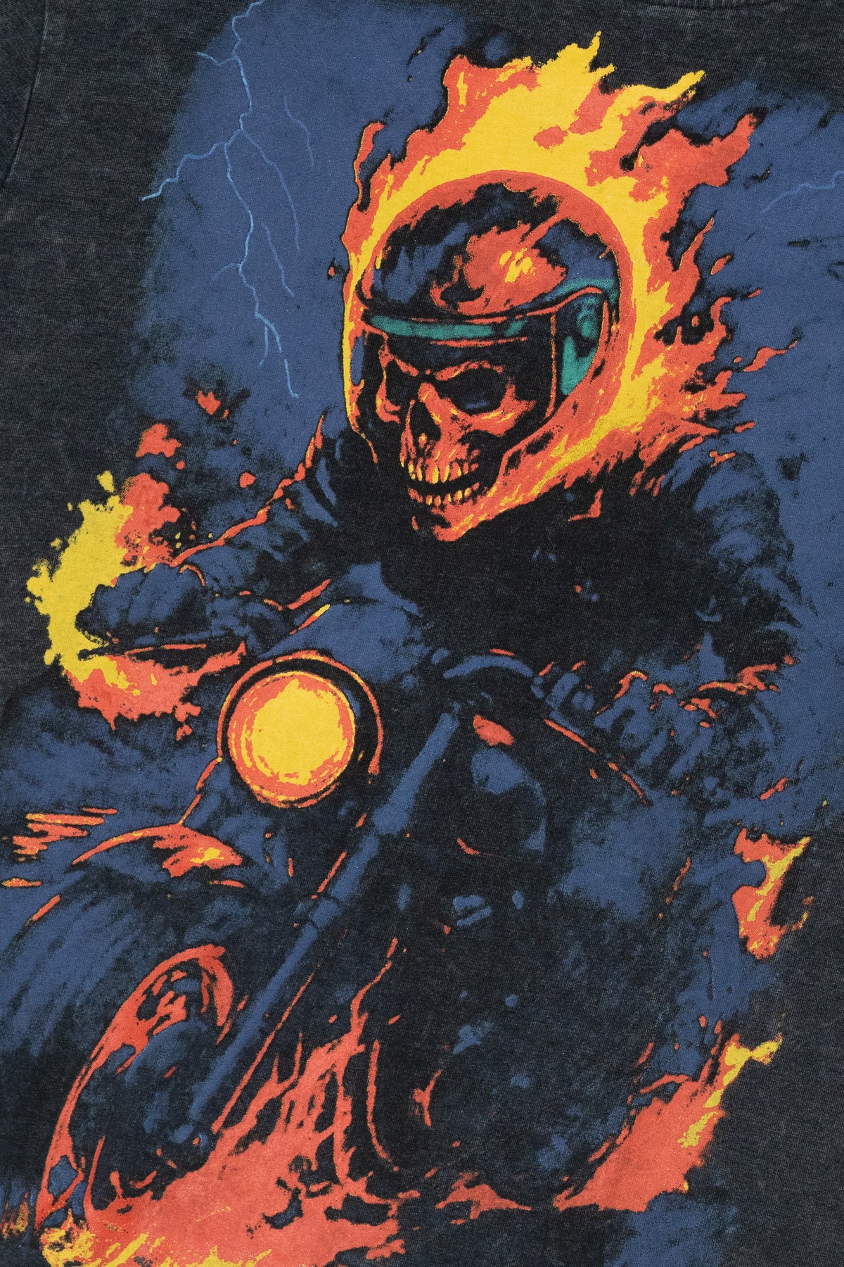 Retro graphic print of a fiery skull in a helmet riding a motorcycle with flames and lightning