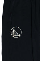 Close-up of black Nike Dri-FIT track pants with San Francisco bridge embroidered logo on thigh and zippered pocket detail.