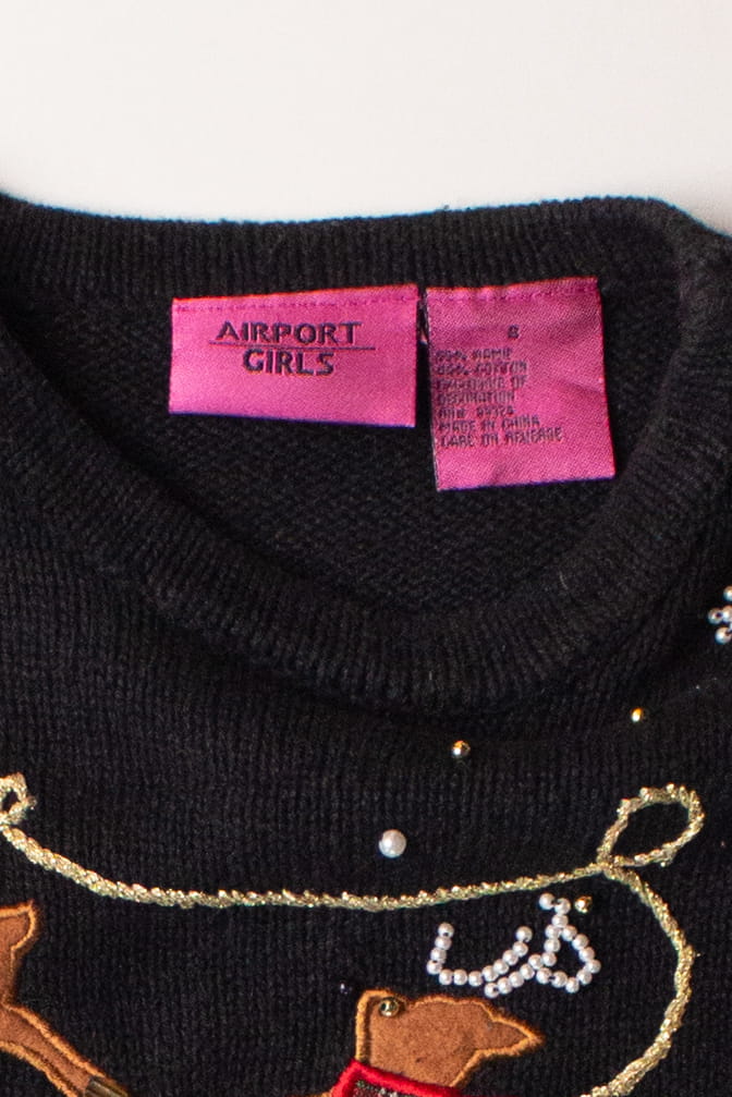 Close-up of kids black ugly Christmas pullover label and embroidered festive reindeer design